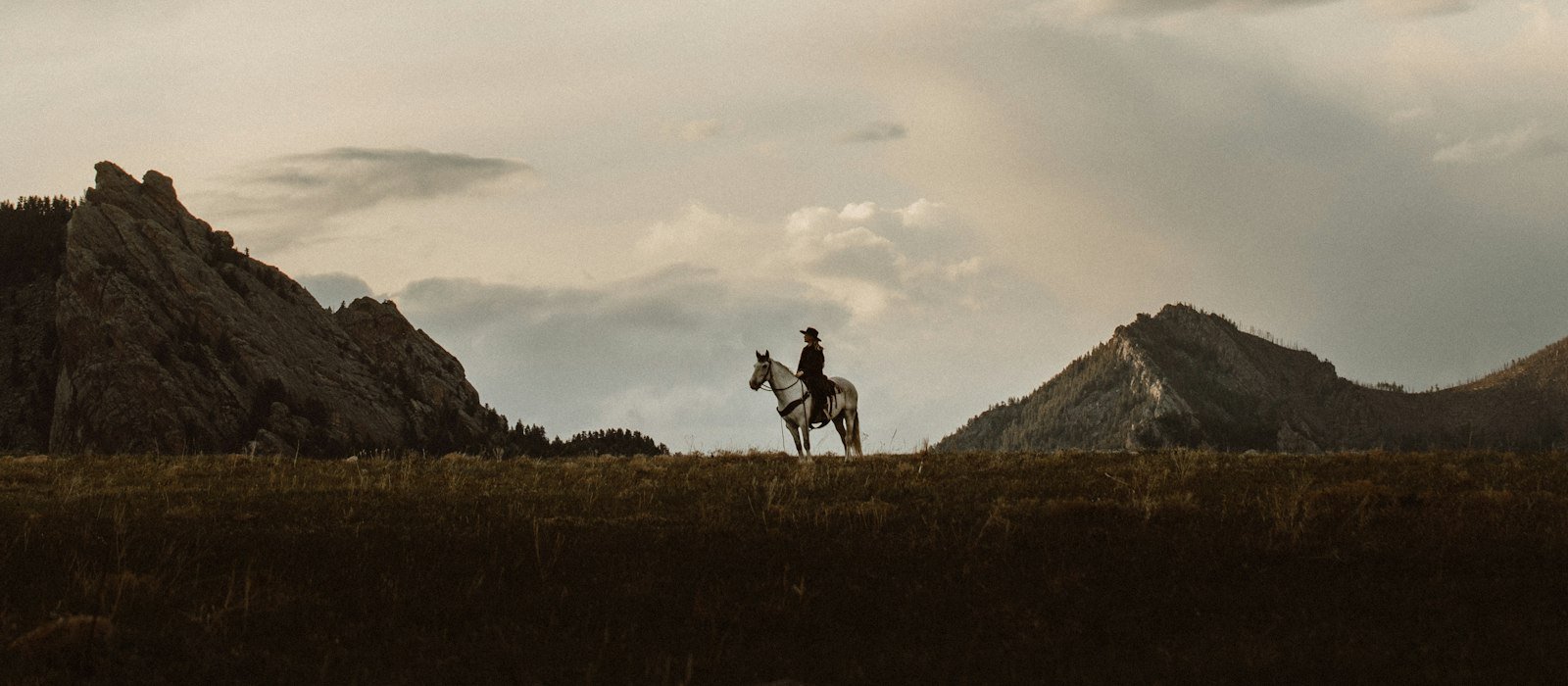 Two ranch hands walking across a green pasture in Colorado