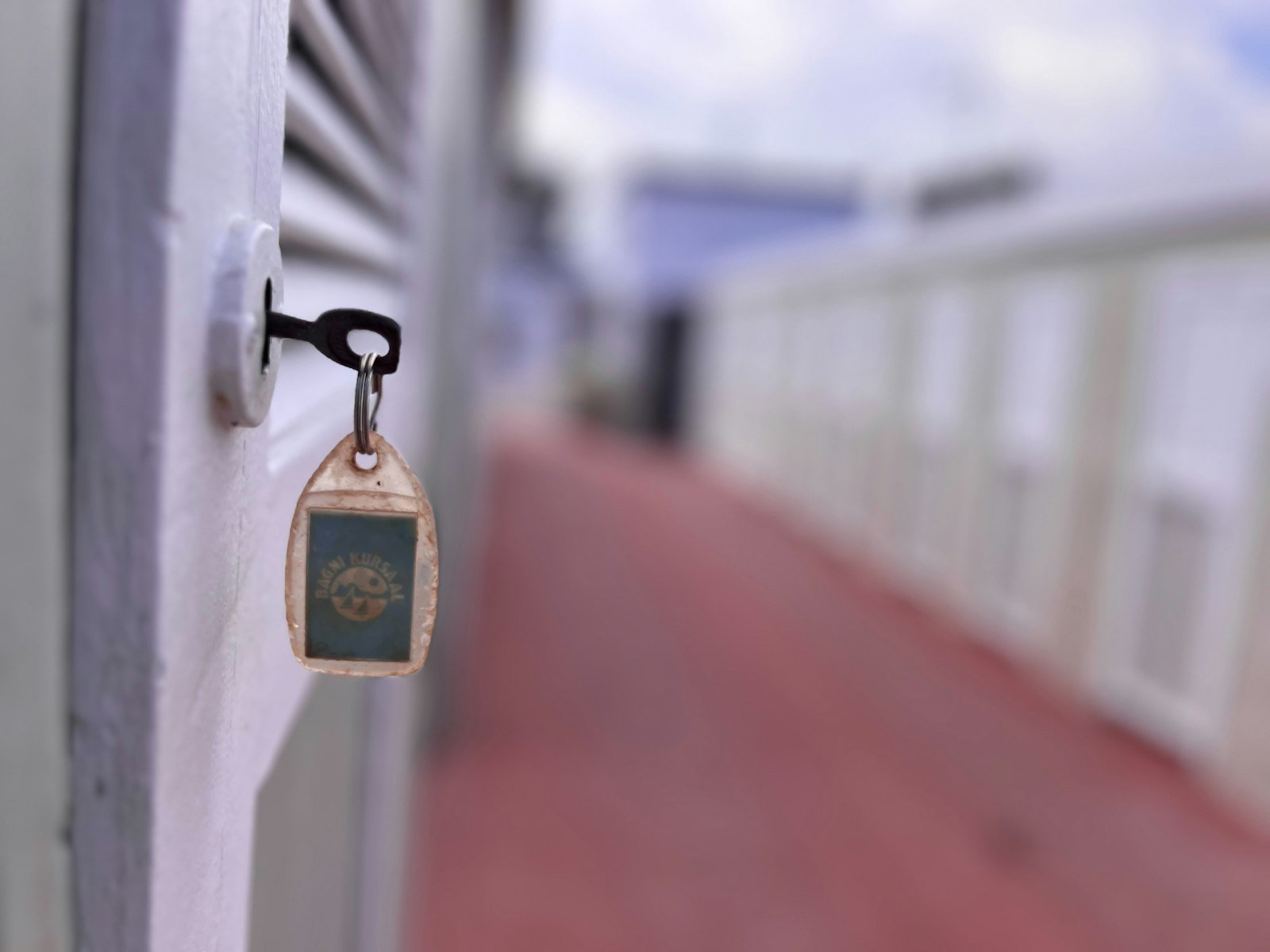Hotel room key in a door lock with a corridor behind