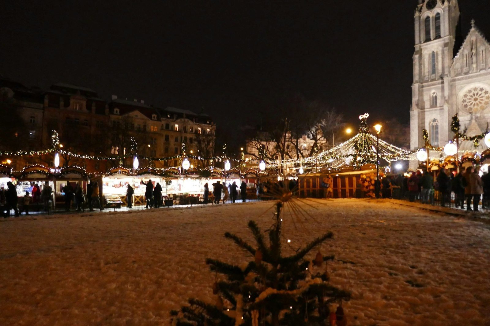 Christmas market stalls and a lit Christmas tree at night in Prague