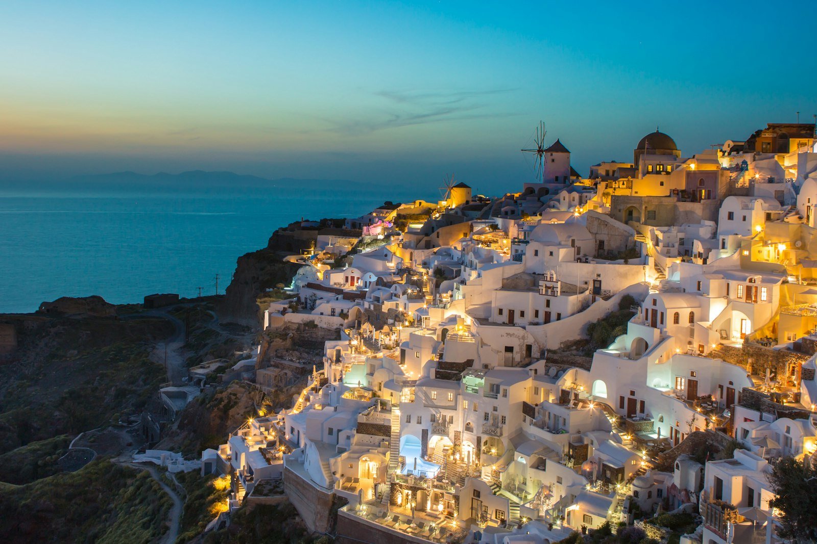 White buildings on a cliffside in Oia, Greece, illuminated by warm evening light, Oia, Greece