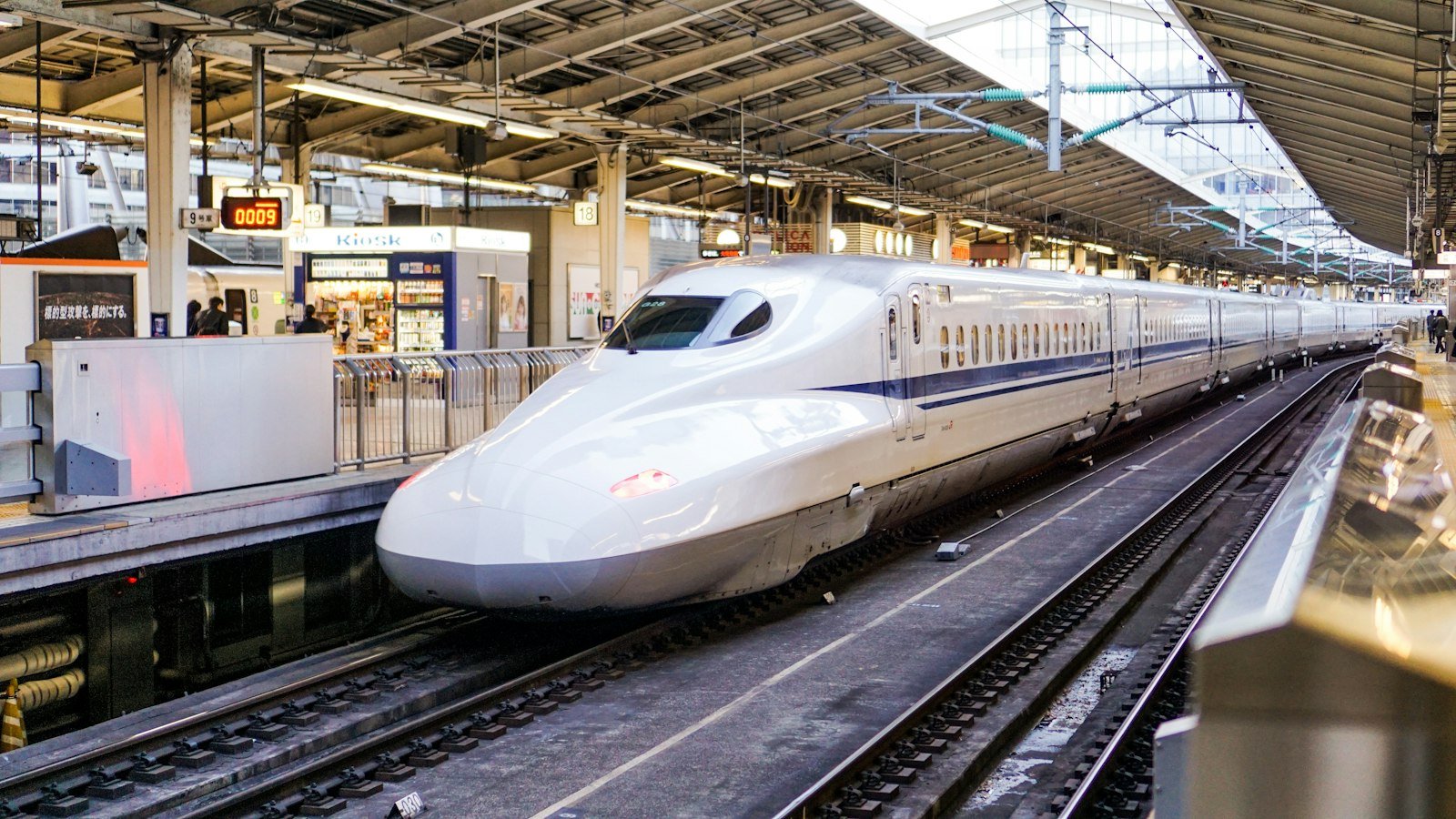 A white Shinkansen bullet train arriving at a modern railway station platform, Tokyo Station, Chiyoda-ku, Japan