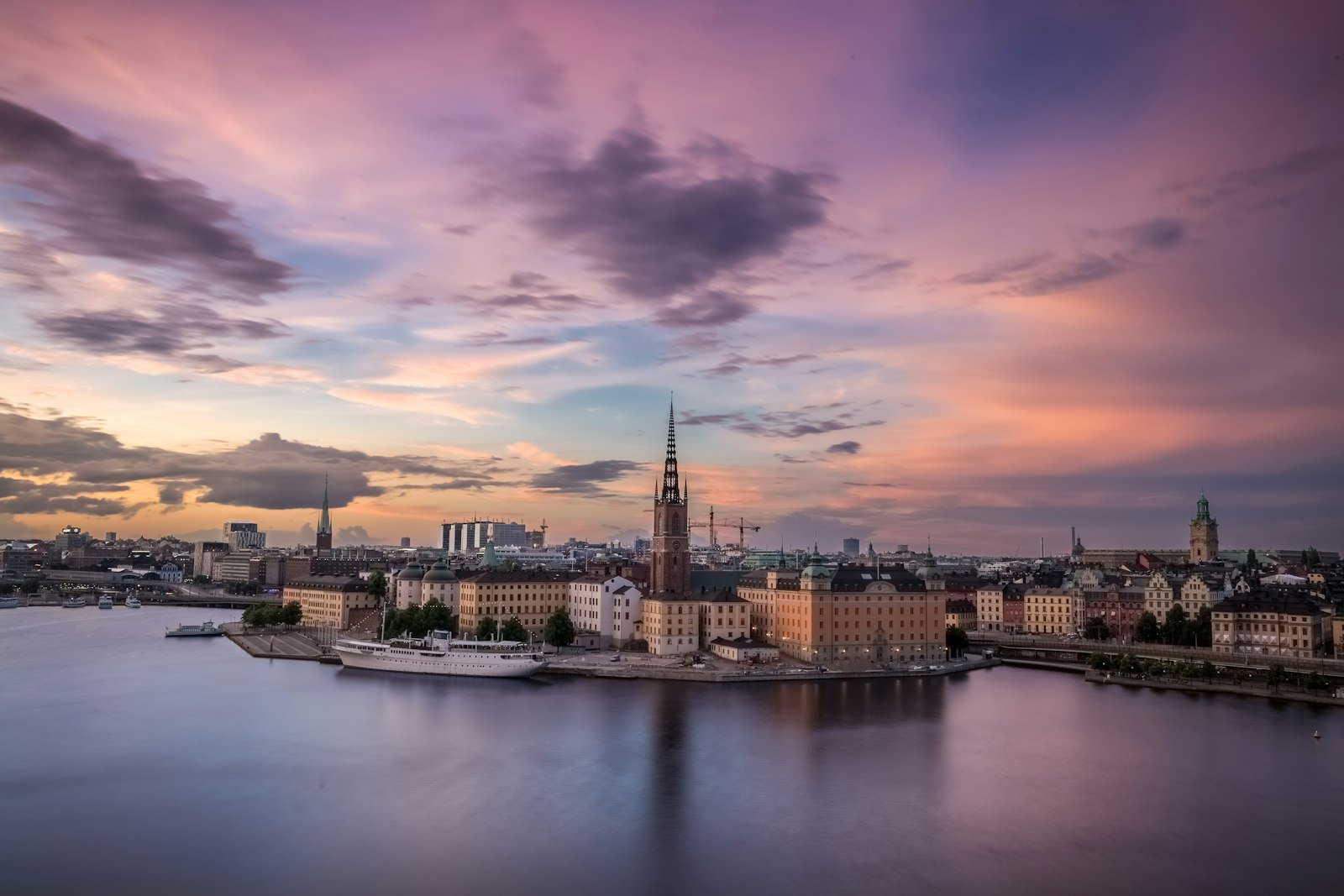 The Riddarholmen Church spire rising above the Stockholm waterfront under a purple sky, Mariaberget, Stockholm, Sweden