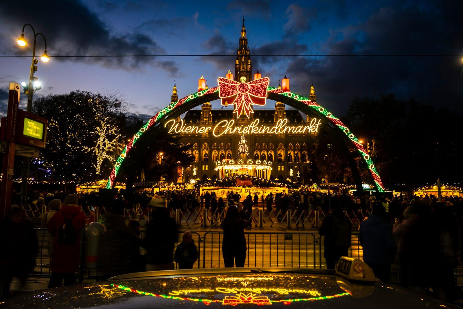 Christmas market archway with an illuminated building at night, Vienna, Austria